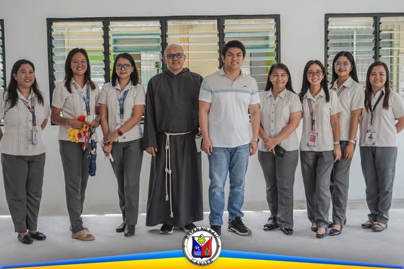 Grupo ng mga tao kasama ang paring naka-itim na damit sa bagong gusali ng Muzon Elementary School