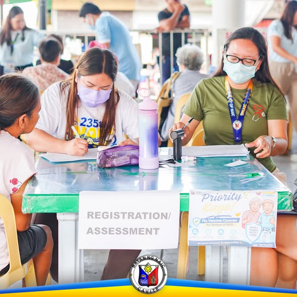 Mga kawani at volunteer sa registration/assessment table ng Flu Vaccine Caravan sa Naic Town Plaza