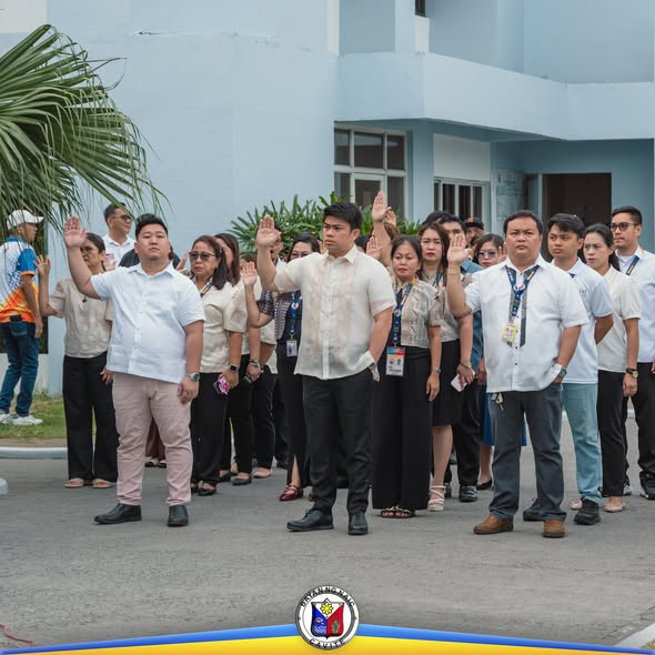 Mga kawani ng bayan na nakataas ang kamay habang nagsasagawa ng flag raising ceremony sa Naic Municipal Hall