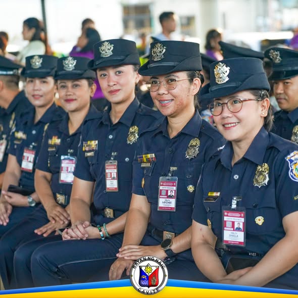 Mga naka-uniporme na kawani habang nakaupo sa flag raising ceremony sa Naic Town Plaza