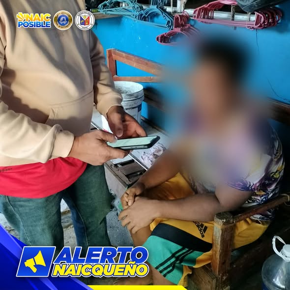 Lalaking may hawak na cellphone habang may nakaupong taong naka-blur sa loob ng bahay, may banner na Alerto Naicqueño