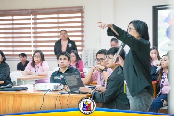 Mga kalahok sa pulong ng Municipal Project Monitoring Committee sa ABC Hall, habang may nagpapaliwanag gamit ang mikropono