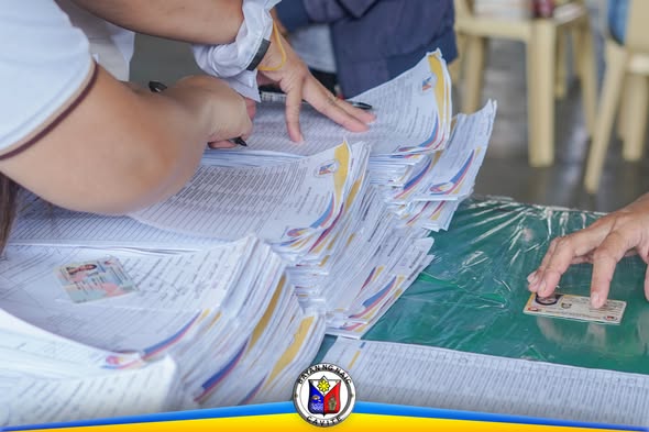 Mga kamay na nag-aayos ng mga papeles at forms sa mesa para sa Medical at Burial Assistance sa Naic Town Plaza