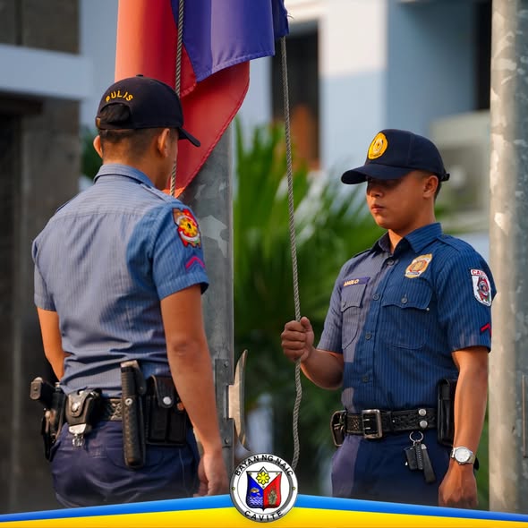 Dalawang nakauniporme habang itinataas ang watawat sa flag raising ceremony sa Naic Municipal Hall
