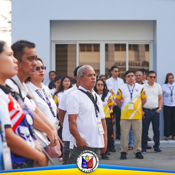 Mga kalahok sa flag raising ceremony sa harap ng Naic Municipal Hall, nakatayo nang maayos sa labas ng gusali