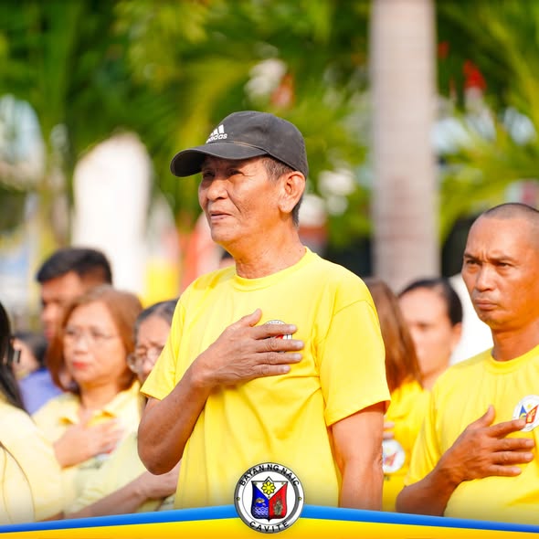 Mga kalahok sa flag raising ceremony na nakatayo at nakahawak sa dibdib habang nagbibigay-galang sa watawat