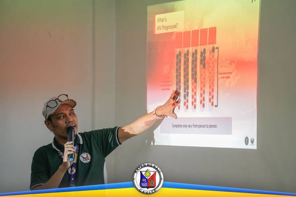 Isang presenter na nagtuturo tungkol sa HIV progression gamit ang projected slide sa HIV/AIDS orientation