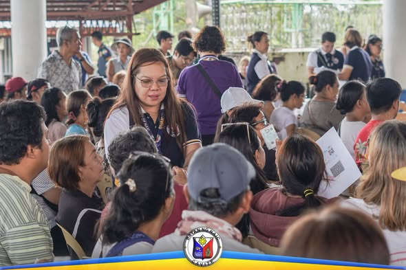 Mga senior citizen na nakaupo at naghihintay habang may staff na nag-aasikaso sa payout sa Naic Town Plaza
