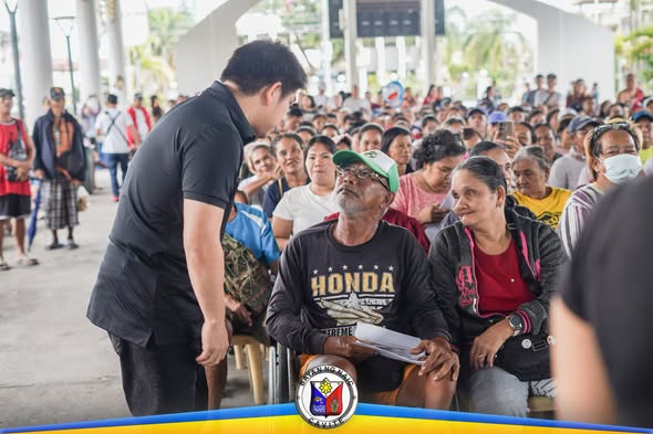 Mga senior citizen na naghihintay sa payout ng tulong sa ilalim ng covered court sa Naic Town Plaza