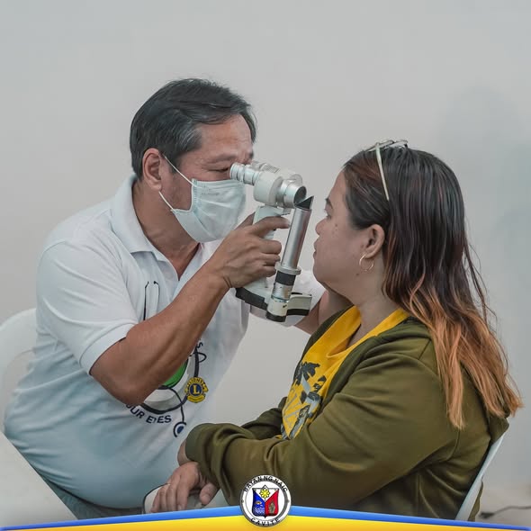 Mmediko na sinusuri ang mata ng isang babae gamit ang eye examination device sa libreng eye check-up sa Naic