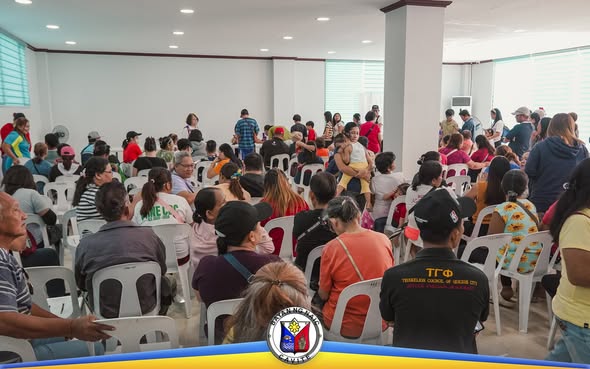 Mga tao na naghihintay ng serbisyo sa loob ng hall para sa libreng eye check-up at cataract screening sa Sabang, Naic