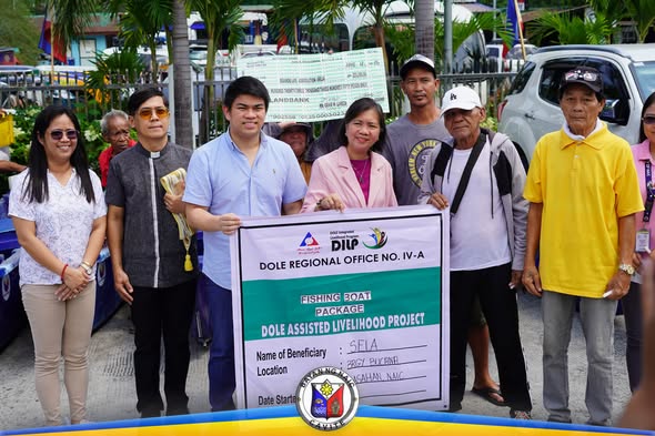 Mga benepisyaryo at opisyal habang hawak ang tarpaulin ng Fishing Boat Package ng DOLE sa Naic
