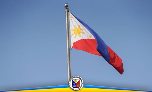 Watawat ng Pilipinas na nakawagayway sa poste laban sa asul na langit, may selyo ng Bayan ng Naic sa ibaba