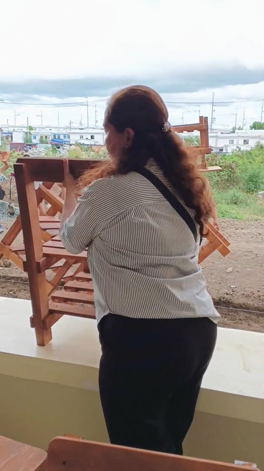 Babaeng inaayos ang wooden armchair sa labas ng paaralan sa Timalan Hillsview Integrated School Annex