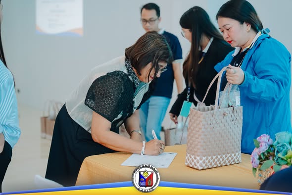 Babaeng pumipirma sa listahan ng dumalo sa registration table ng League of Assessors sa Naic