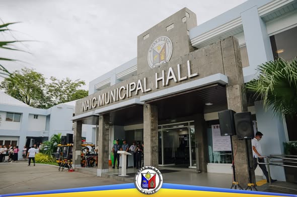 Naic Municipal Hall, may podium at mga tao sa harap ng gusali habang isinasagawa ang Flag Raising Ceremony