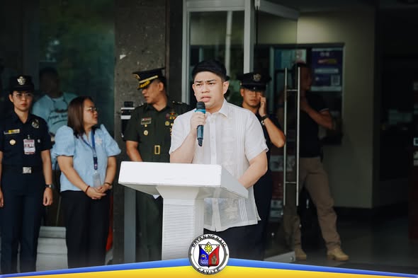 Isang tagapagsalita sa podium habang nagsasalita sa flag raising ceremony sa harap ng Naic Municipal Hall