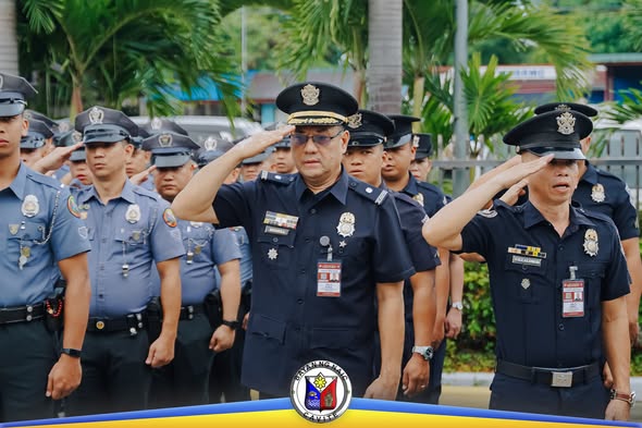Mga uniformadong opisyal na nagsasaludo habang isinasagawa ang Flag Raising Ceremony sa Naic