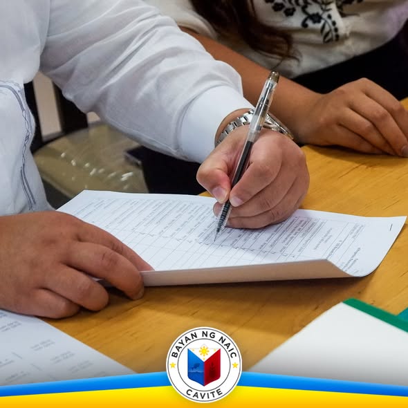 Kamay na nagsusulat sa isang form sa mesa habang isinasagawa ang turnover ceremony sa Naic