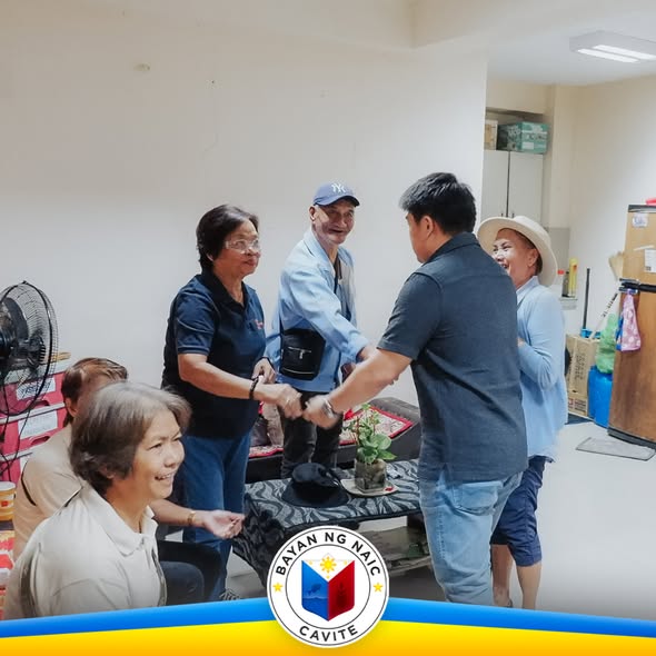 Mga kababayan na nakikipagkamay sa loob ng Municipal Hall ng Naic habang may mga nakikinig at nakangiti
