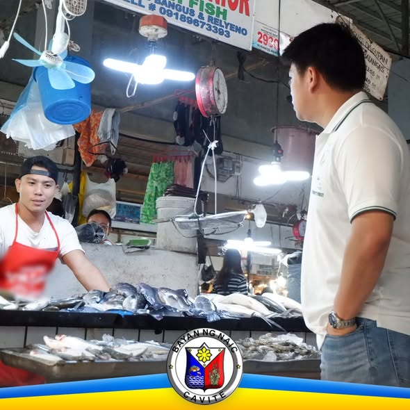 Mga tindero at isang opisyal na nakatingin sa mga sariwang isda sa palengke ng Naic