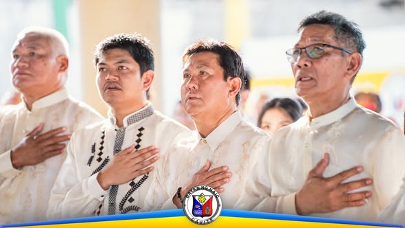 Mga lalaking naka-barong na nakatayo at nakahawak sa dibdib habang nagpupugay sa flag-raising ceremony sa Naic