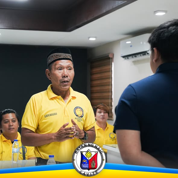 Mga tao sa pulong habang nagsasalita ang lalaking naka-dilaw na polo sa loob ng opisina sa Naic