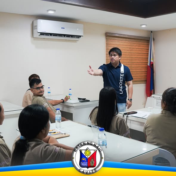 Lalaki na nagsasalita at nagtuturo sa grupo ng mga nakaupo sa loob ng silid-pulungan sa Naic