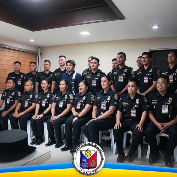 Mga tauhan ng BFP Naic na nakahanay para sa larawan sa loob ng opisina, may logo ng Bayan ng Naic