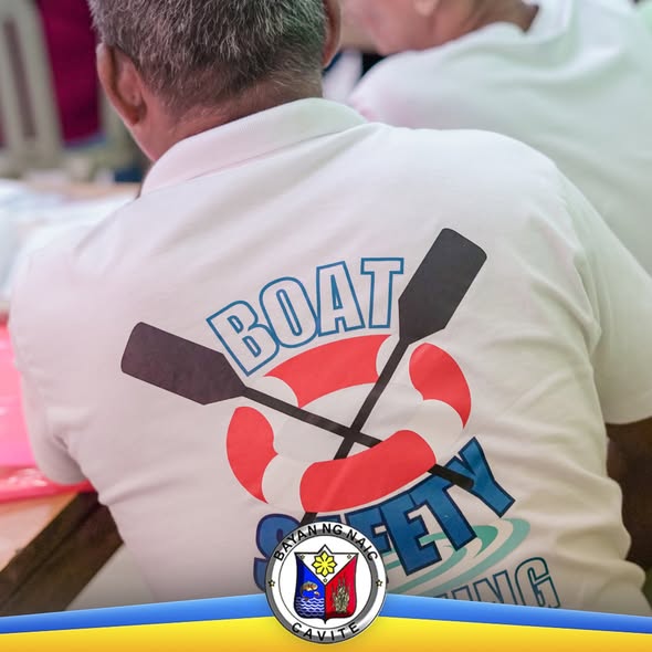 Graphic: Likod ng polo shirt na may print na 'Boat Safety' at krus na sagwan, may logo ng Bayan ng Naic sa ibaba