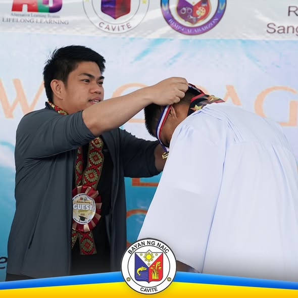 Panauhing nagsasabit ng medalya sa isang nagtapos sa seremonya ng pagtatapos ng ALS