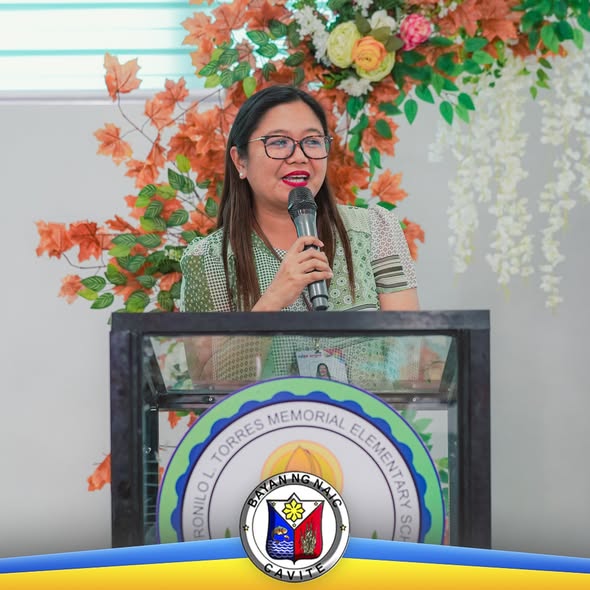 Babaeng nagsasalita sa mikropono sa podium sa harap ng floral backdrop, sa Division Convergence sa Naic