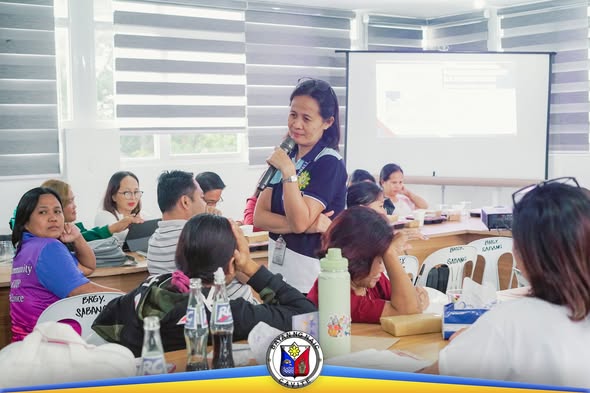 Nagsasalita ang isang babae gamit ang mikropono sa mandatory training ng mga kooperatiba sa Sabang Multipurpose Hall