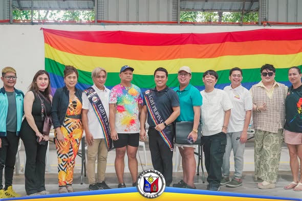 Grupo ng mga miyembro ng LGBT Pilipinas One Naic na nagpose sa harap ng rainbow flag matapos ang halalan