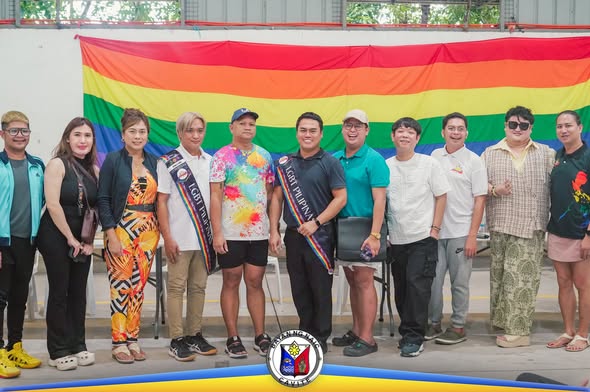 Grupo ng mga miyembro ng LGBT Pilipinas One Naic sa harap ng rainbow flag matapos ang pagpupulong at halalan