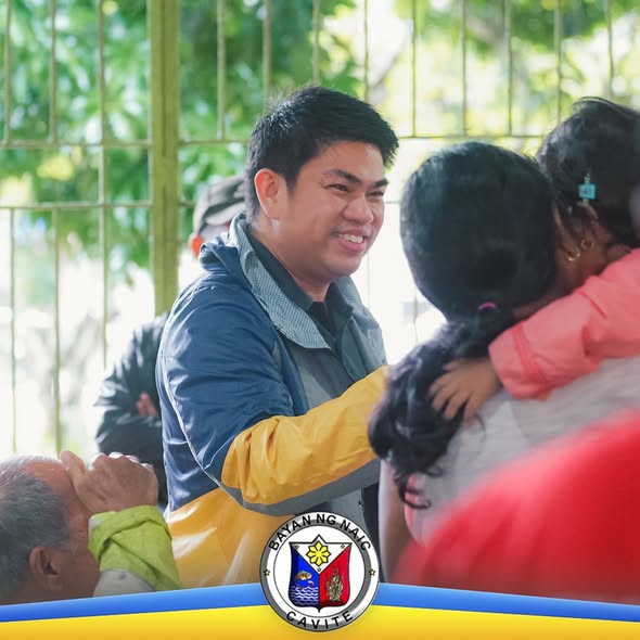 Litrato: Nakangiting lalaki na yumayakap sa batang babae sa relief operation, may grille sa likod