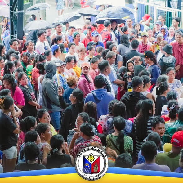 Maraming tao na nakapayong at nakapila habang namamahagi ng tulong sa relief operations sa Naic