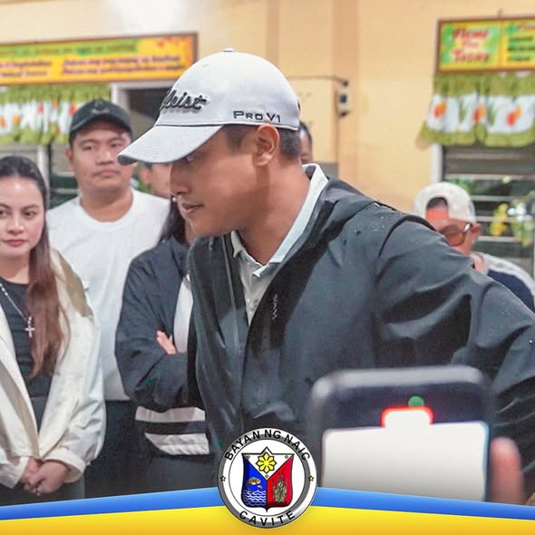 Litrato: Lalaking naka-puting cap at jacket habang nakikiisa sa relief operations sa Naic, may mga tao sa paligid