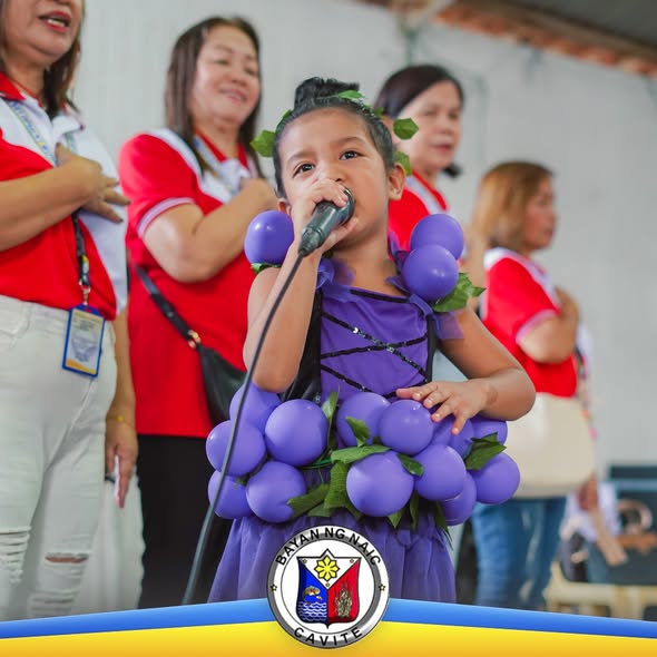 Batang nakasuot ng ubas na costume habang nagsasalita sa mikropono sa Nutrition Month celebration sa Naic