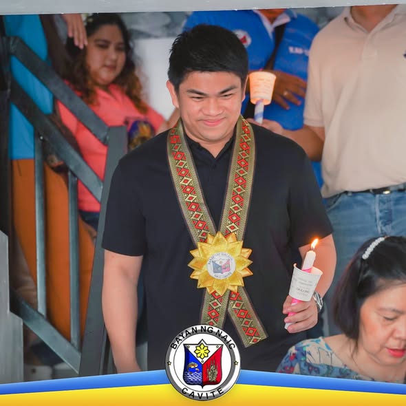Lalaking may suot na sash at hawak na kandila habang nakikiisa sa pagdiriwang sa Barangay Halang, Naic