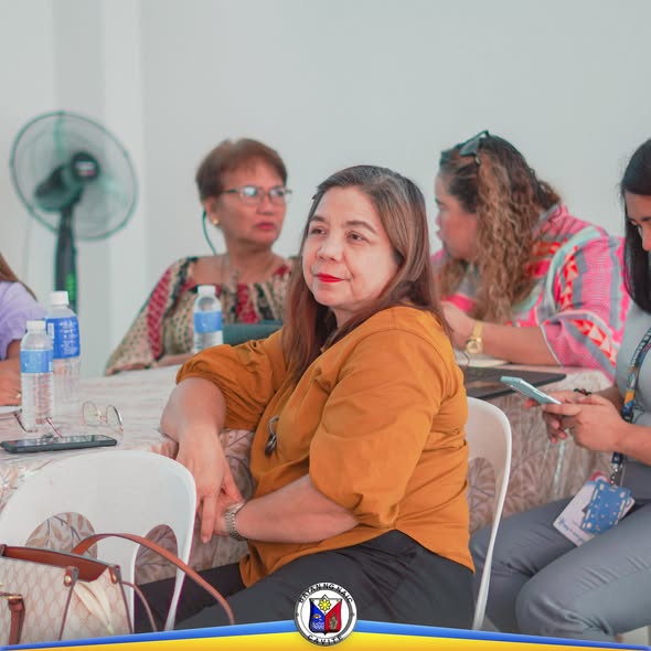 Mga kalahok sa orientation ng Bakuna Eskwela na nakaupo sa mesa habang nakikinig sa loob ng silid