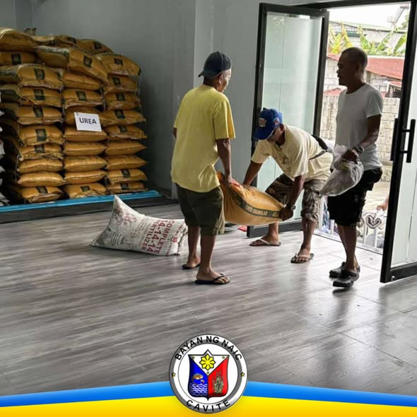 Mga magsasaka na nagbubuhat ng fertilizer sa loob ng bodega ng agricultural inputs sa Naic