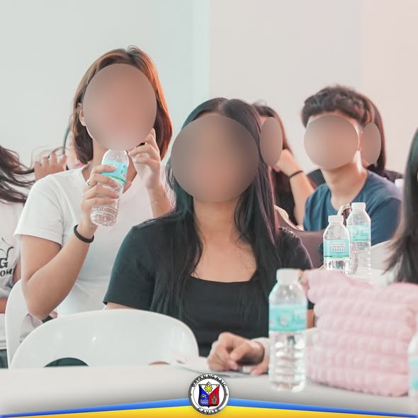 Mga kabataang babae na nakaupo at may hawak na bote ng tubig habang dumadalo sa Girl Child Week 2025 sa Naic