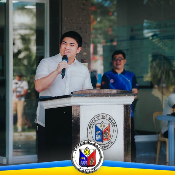 Lalaking nagsasalita sa podium na may selyo ng Office of the Mayor sa harap ng Municipal Hall ng Naic habang nagaganap ang…