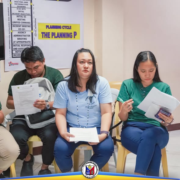 Mga kalahok sa pagsasanay na nagbabasa ng papel habang nakaupo sa silid-pulungan ng Naic RHU