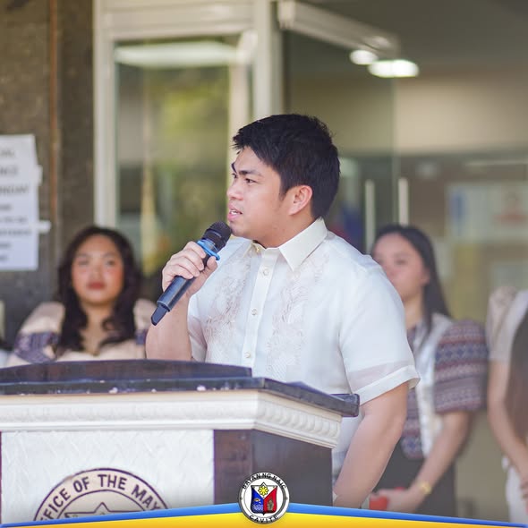Lalaki na nagsasalita sa mikropono sa podium habang nasa Flag Raising Ceremony ng Naic