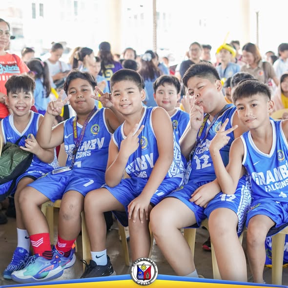 Mga batang manlalaro ng basketball na naka-blue na jersey habang nagpapakuha ng larawan sa Sports Festival sa Naic