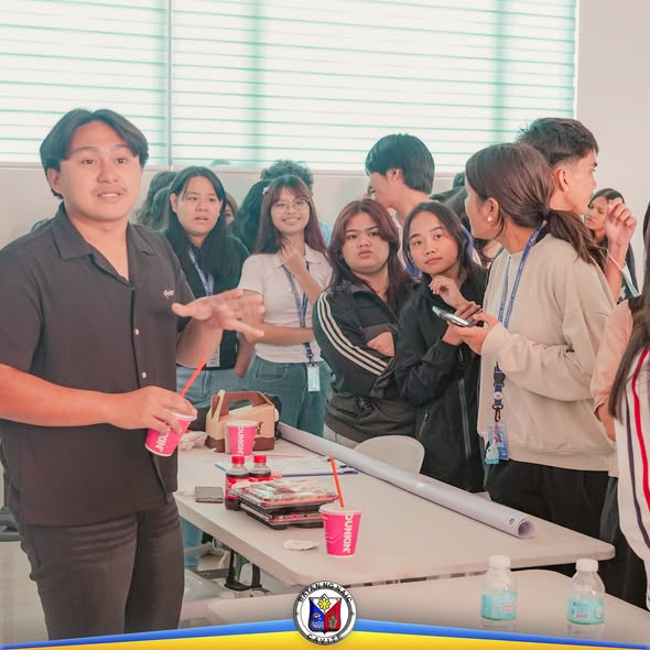 Mga kabataan na may lanyard habang nagtitipon sa training room ng RHU-Naic, may mesa na may baso at tubig