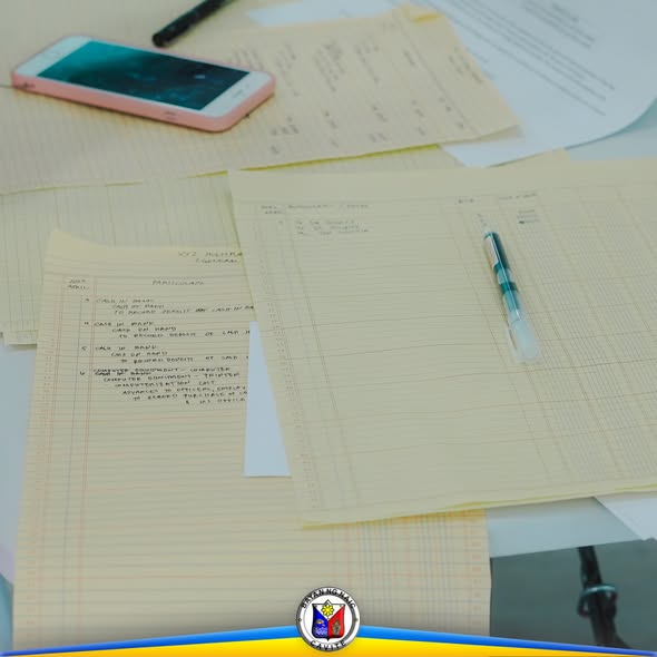 Mga nakasulat na ledger sheet at panulat sa mesa habang may seminar sa accounting para sa kooperatiba