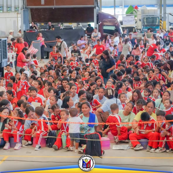 Maraming batang nakaupo sa sahig habang nanonood ng Yan Kiddie Show sa loob ng malaking bulwagan sa Naic